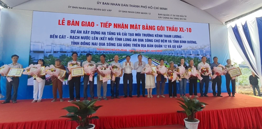 Lãnh đạo địa phương tặng hoa cảm ơn những trường hợp bàn giao mặt bằng cho dự án cải tạo môi trường kênh Tham Lương - Bến Cát - rạch Nước Lên. Ảnh: NGUYỄN CHÂU