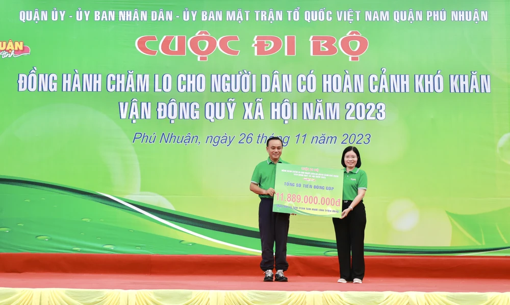 Lãnh đạo quận Phú Nhuận tiếp nhận bảng tượng trưng gần 12 tỉ đồng ủng hộ từ buổi đi bộ gây quỹ. Ảnh: DI LINH Lãnh đạo quận Phú Nhuận tiếp nhận bảng tượng trưng 11,889 tỉ đồng ủng hộ từ buổi đi bộ gây quỹ. Ảnh: DI LINH