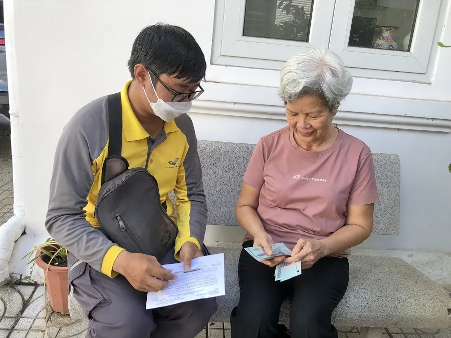 Nhân viên bưu điện chi trả lương hưu bằng tiền mặt tại nhà cho người hưởng lương hưu