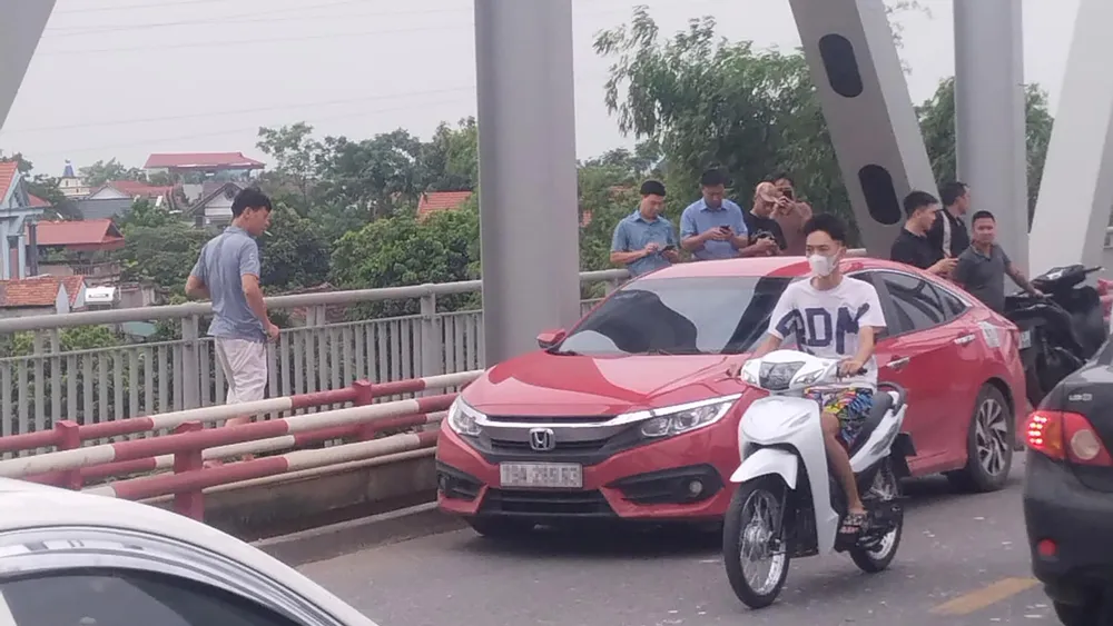 Chiếc ô tô màu đỏ nam thanh niên để lại rồi nhảy sông. Ảnh CTV Diễn biến mới vụ người đàn ông để ô tô trên cầu rồi nhảy xuống sông Hồng.jpg