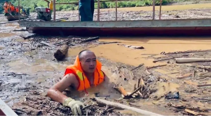 Cán bộ công an bơi giữa dòng củi rác tìm kiếm người mất tích. Ảnh: AN NINH ĐIỆN BIÊN Điện Biên Công an bơi giữa dòng củi, rác tìm người mất tích do lũ quét.jpg