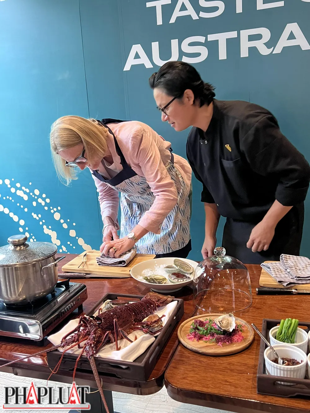 Đầu bếp Luke Nguyễn hướng dẫn Tổng Lãnh sự Úc tại TP Hồ Chí Minh Sarah Hooper tách vỏ một con hàu. Ảnh: PLO