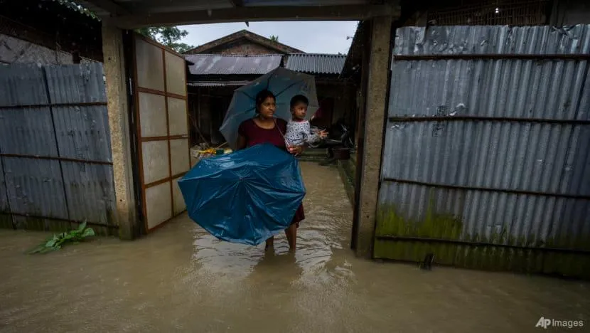 Một phụ nữ bồng con đứng trong dòng nước lũ đợi binh sĩ đến giải cứu ở làng Jalimura, TP Gauhati, bang Assam (Ấn Độ) ngày 18-6. Ảnh: AP Một phụ nữ bồng con đứng trong dòng nước lũ đợi binh sĩ đến giải cứu ở làng Jalimura, TP Gauhati, bang Assam (Ấn Độ) ngày 18-6. Ảnh: AP