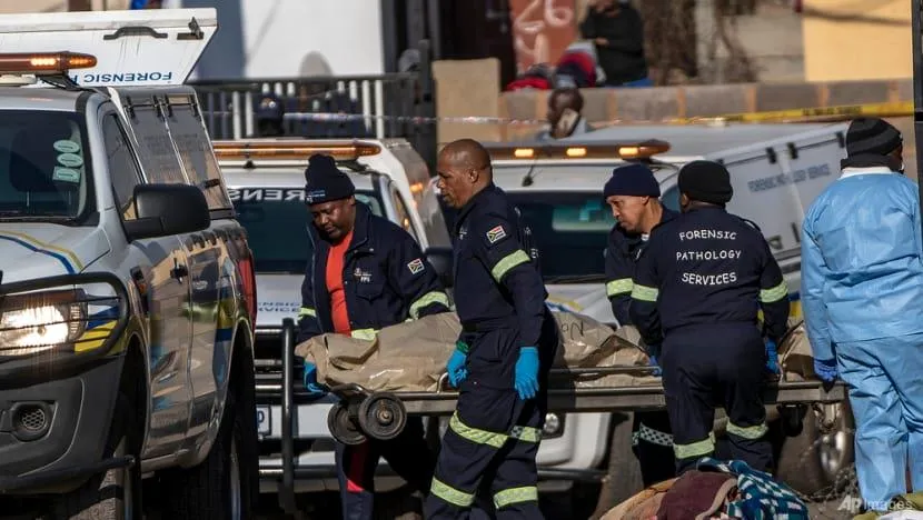 Một thi thể được đưa ra khỏi hiện trường vụ xả súng tại quán bar ở Soweto, Nam Phi, ngày 10-7. Ảnh: AP