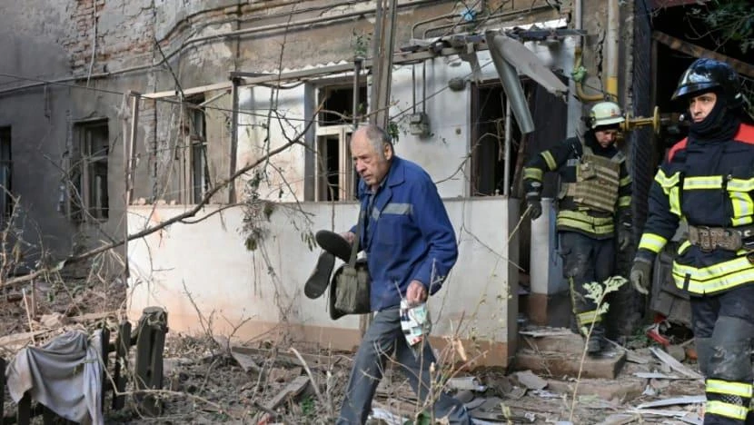 Một người dân địa phương mang theo thuốc trong túi nhựa khi rời khỏi một tòa nhà dân cư sau trận pháo kích ở tỉnh Kharkiv vào ngày 23-7. Ảnh: AFP