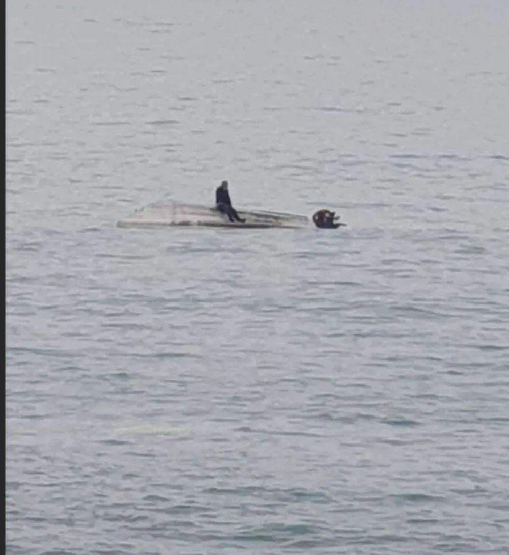 Một nạn nhân sống sót sau vụ lật thuyền ngồi đợi giải cứu trên mũi con thuyền. Ảnh: TWITTER Một nạn nhân sống sót sau vụ lật thuyền ngồi đợi giải cứu trên mũi con thuyền. Ảnh: TWITTER