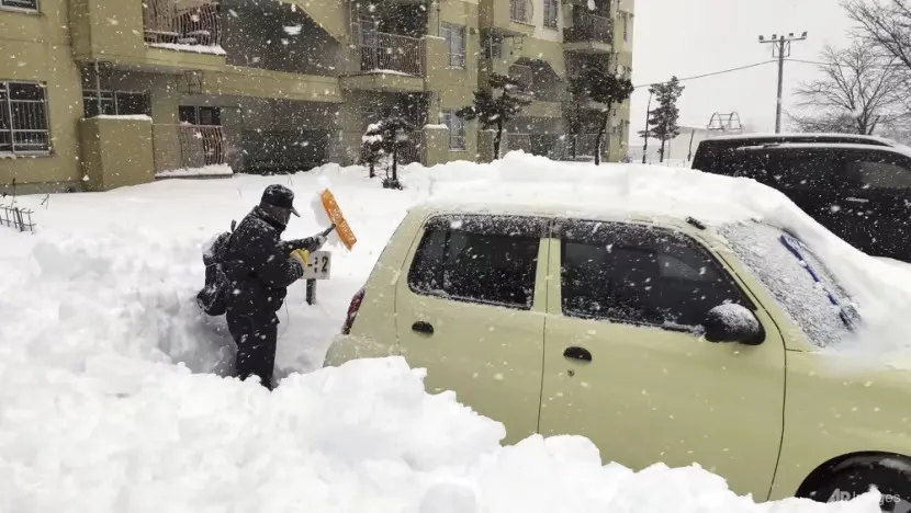 Một người dân dọn dẹp tuyết xung quanh một chiếc ô tô tại một bãi đậu xe ở TP Kitami, tỉnh Hokkaido, phía bắc nước Nhật, vào ngày 24-12. Ảnh: AP