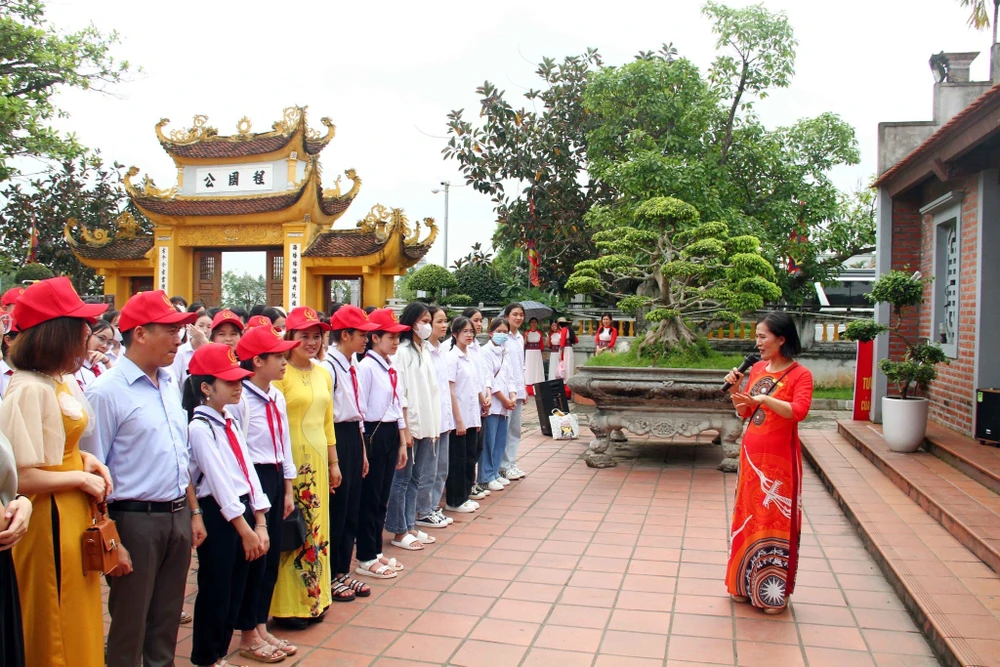 Các em học sinh đang nghe thuyết minh về khu di tích. Ảnh: NGỌC SƠN