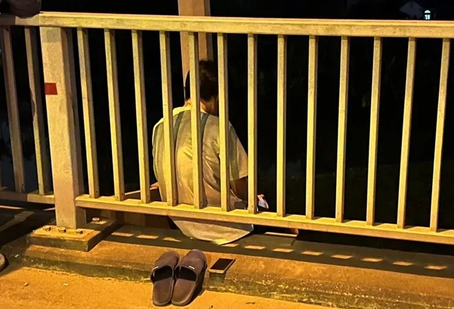 Nam thanh niên ngồi ngoài lan can, có ý định nhảy cầu tự tử