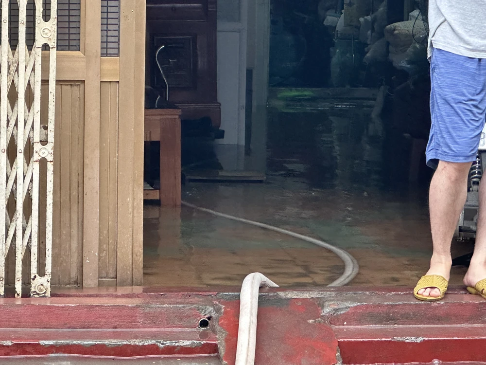 Nước ngập vào nhà khiến một gia đình phải dùng máy bơm hút nước ra. Ảnh: Ngọc Sơn hai-phong-trong-con-mua-lon-cay-xa-cu-do-nat-bet-o-to-7.jpg