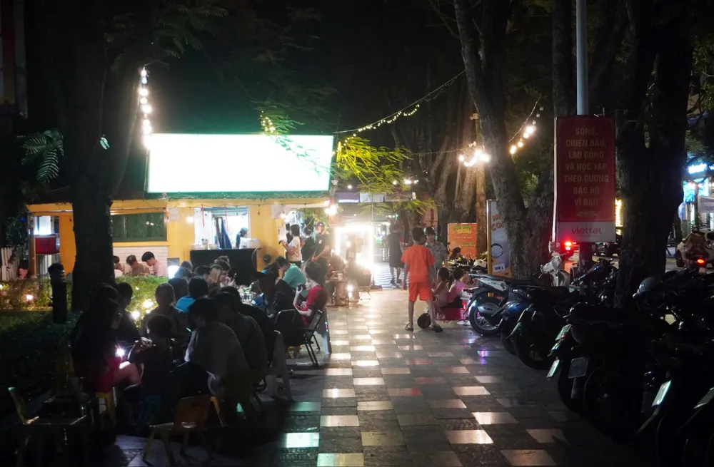 Dù vậy, theo quan sát của PLO, trên thực tế, nhiều kios đã kê thêm rất nhiều bàn ghế ra vỉa hè. Một số quán cafe hai bên đường Trần Phú, Quang Trung còn tranh thủ đưa bàn ghế sang dải vườn hoa đối diện để làm ăn. Xe máy leo lên dải vườn hoa, chen chúc mỗi tối, không còn chỗ cho người đi bộ. Ảnh: Ngọc Sơn nhuc-nhoi-tai-dai-vuon-hoa-trung-tam-thanh-pho-hai-phong-6.jpg