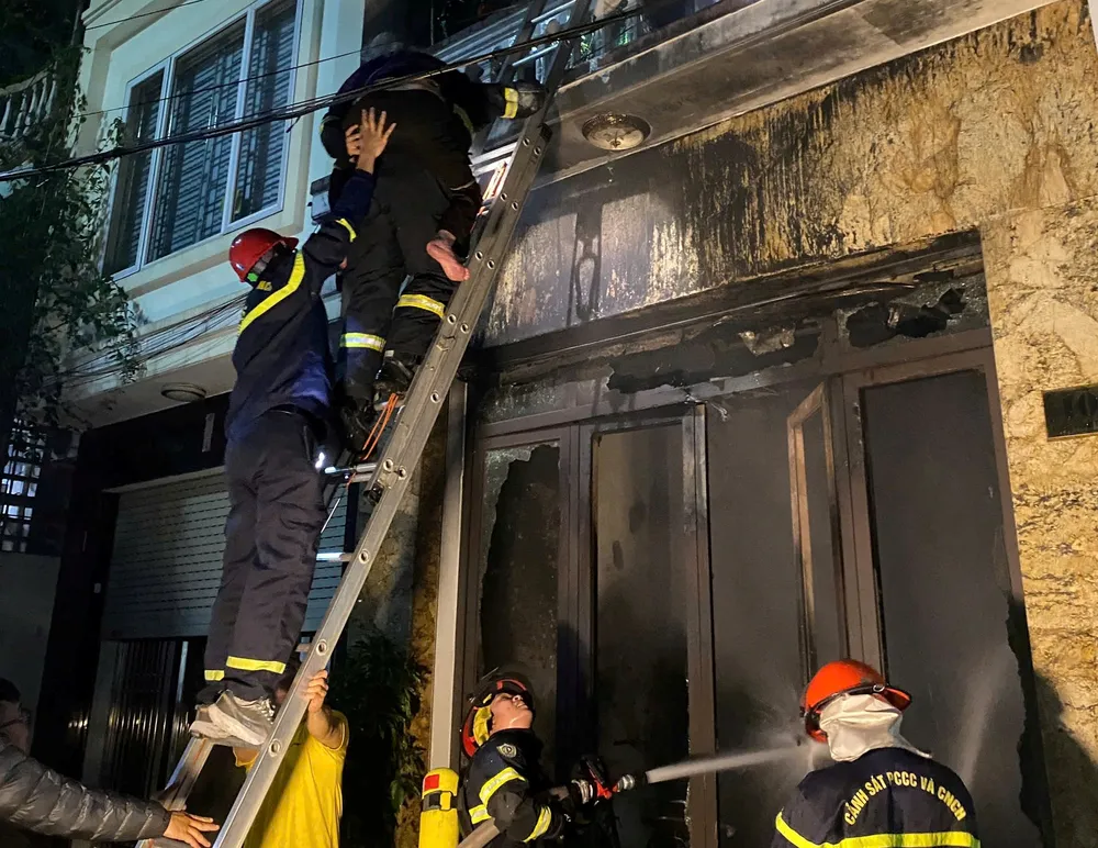 Các chiến sĩ PCCC cõng cụ bà 94 tuổi khỏi ngôi nhà. Ảnh: CAHP