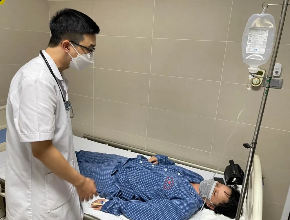 Bác sĩ Nguyễn Đình Tới đang thăm hỏi sức khoẻ bệnh nhân sốt xuất huyết. Ảnh: NHƯ LOAN