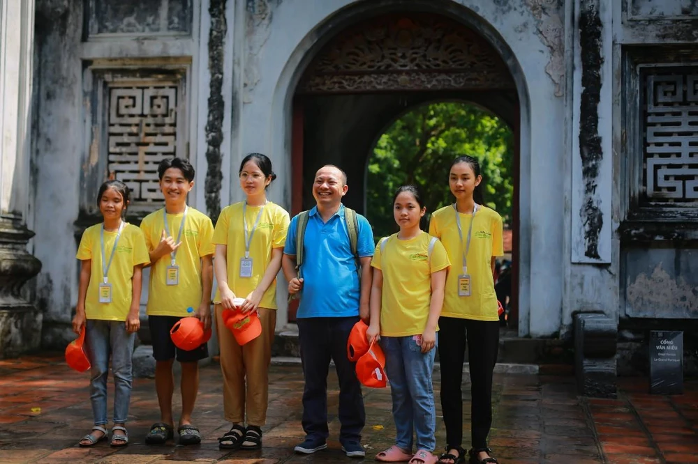 Anh Vũ Hồng Khanh chụp hình cùng các em học sinh do anh nhận đỡ đầu nuôi ăn học. Ảnh: NHƯ LOAN