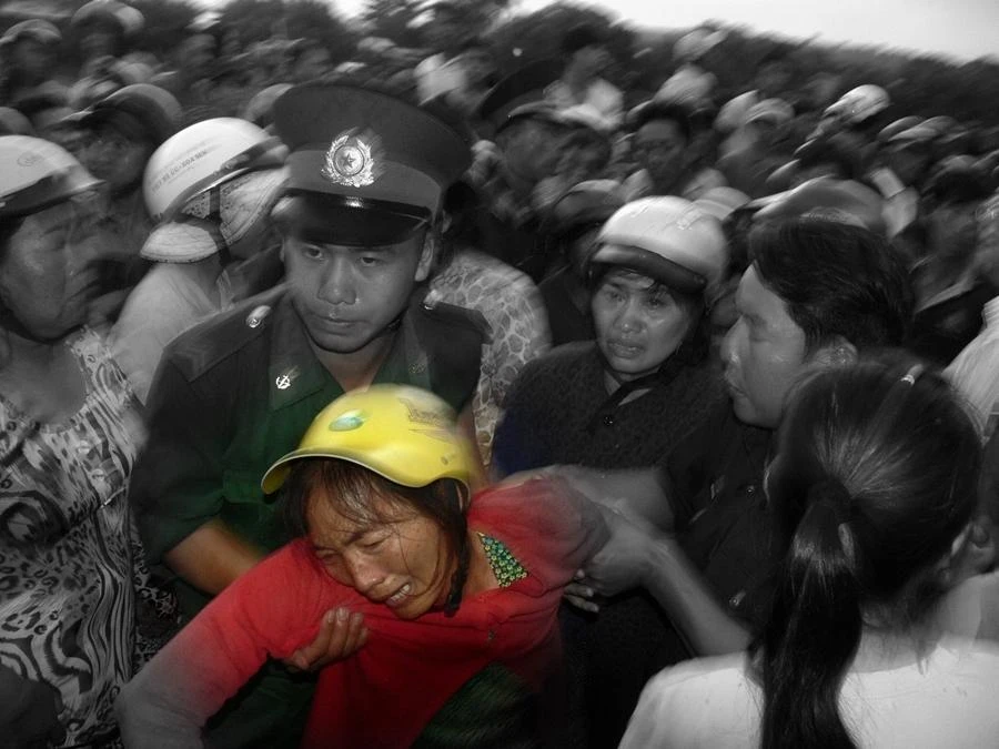 Một chiến sĩ Bộ đội biên phòng dìu người phụ nữ vừa nhận tin chồng mất tích trong vụ chìm tàu tháng 7-2014. Ảnh PHƯƠNG NAM.