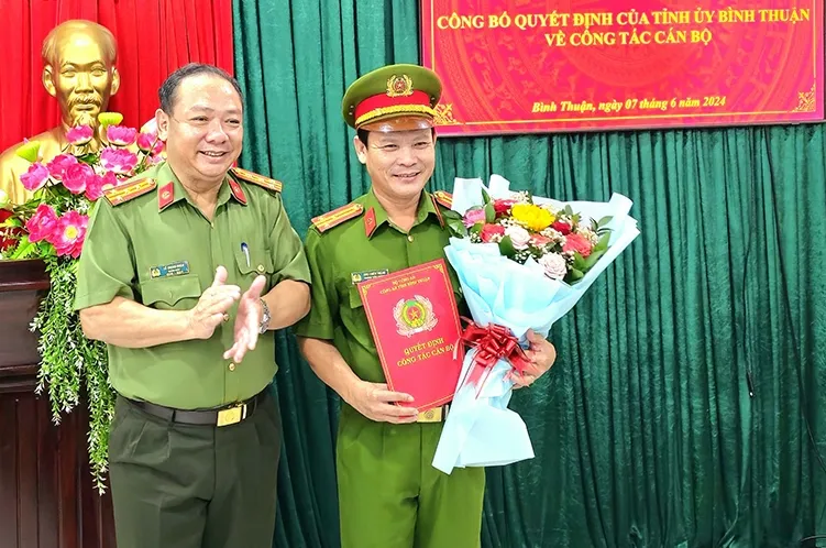 Đại tá Lê Quang Nhân, Giám đốc Công an Bình Thuận trao quyết định và tặng hoa chúc mừng Thượng tá Ung Chiêu Thành. Ảnh CABT. tỉnh Bình Thuận