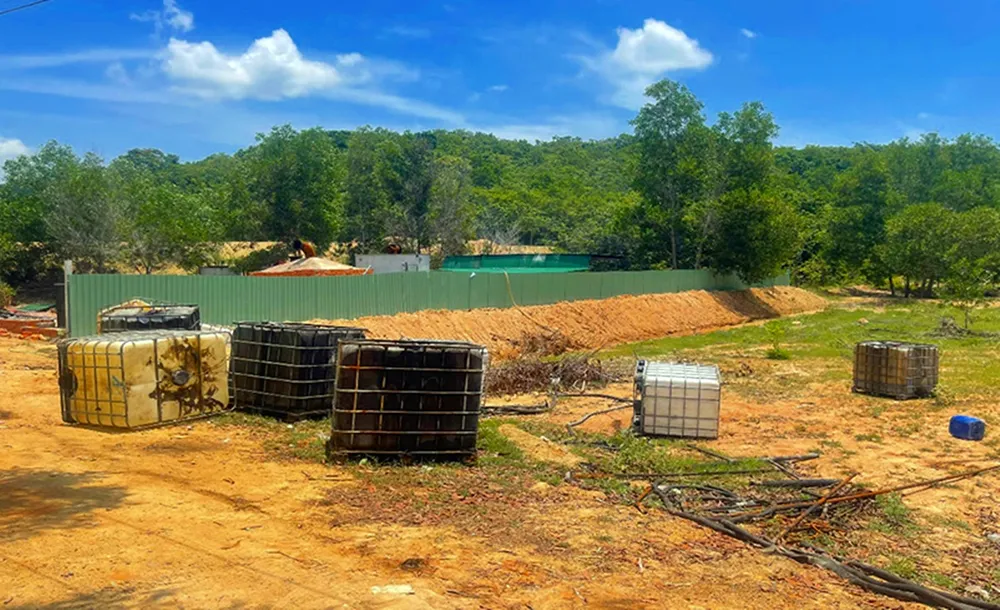 Khu vực tái chế nhớt thải nằm sát bìa rừng được đắp đất, dựng tôn để che chắn. tái chế nhớt