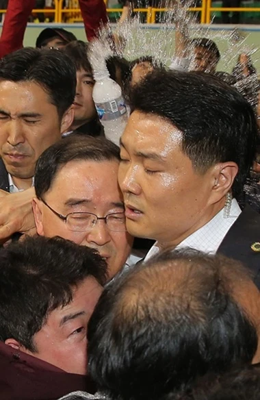 Các vệ sĩ che chắn cho Thủ tướng Chung Hong-won khi ông bị thân nhân hành khách phà Sewol ném chai nước tại đảo Jindo.