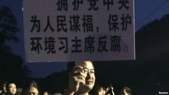 Trung Quốc: Người biểu tình đốt xe cảnh sát, 39 người bị thương ảnh 1 A demonstrator holds a placard during a protest against the construction of a waste incinerator in Hangzhou, Zhejiang province May 7, 2014.
