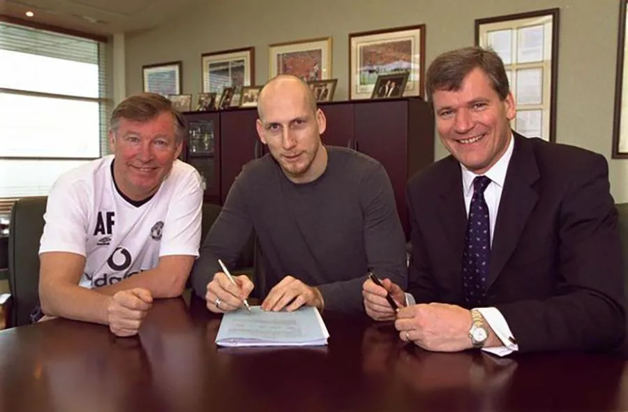 Stam đặt bút ký vào bản hợp đồng với Man Utd dưới sự chứng kiến của Sir Alex và David Gill. ẢNH: PA