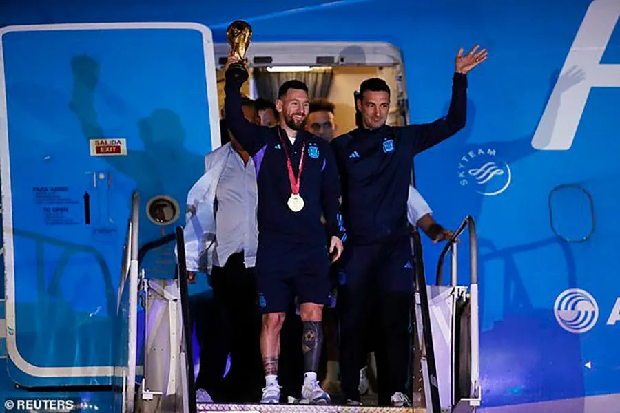 Lionel Messi cầm cúp vô địch và đeo HCV cùng HLV Lionel Scaloni bước ra máy bay đầu tiên. ẢNH: REUTERS