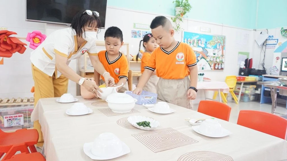 Cô Ngũ Tố Linh, giáo viên lớp lá 5 cho biết, giờ ăn của trẻ mầm non được tổ chức rất đa dạng. Lớp chọn hình thức tổ chức bữa ăn gia đình để tạo nên sự ấm cúng, gần gũi giữa các bé với nhau. Các bé sẽ ăn theo nhóm. Mỗi nhóm khoảng 4 đến 6 bé. Nhóm các bé ăn chậm sẽ được bố trí ăn đầu tiên. Các nhóm sẽ tự bày biện bữa ăn từ khiêng bàn, trải khăn đến sắp xếp chén bát...và lên món. Trong quá trình ăn, các bé sẽ hỗ trợ lẫn nhau. Cô Ngũ Tố Linh, giáo viên lớp lá 5 cho biết, giờ ăn của trẻ mầm non được tổ chức rất đa dạng. Lớp chọn hình thức tổ chức bữa ăn gia đình để tạo nên sự ấm cúng, gần gũi giữa các bé với nhau. Các bé sẽ ăn theo nhóm. Mỗi nhóm khoảng 4 đến 6 bé. Nhóm các bé ăn chậm sẽ được bố trí ăn đầu tiên. Các nhóm sẽ tự bày biện bữa ăn từ khiêng bàn, trải khăn đến sắp xếp chén bát...và lên món. Trong quá trình ăn, các bé sẽ hỗ trợ lẫn nhau.