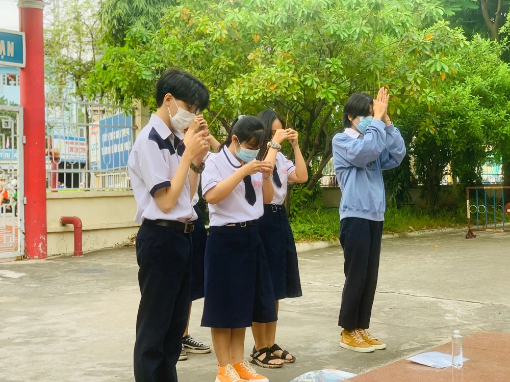 Học sinh khấn nguyện trước giờ thi bên tượng cụ Mạc Đỉnh Chi tại điểm thi trường THPT Mạc Đỉnh Chi. Ảnh: THẢO PHƯƠNG