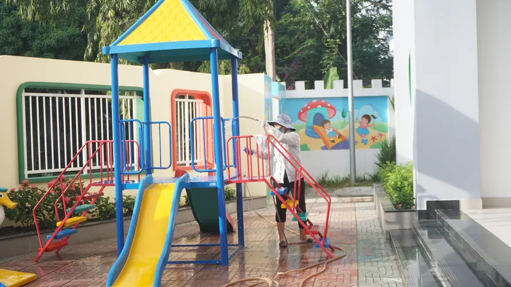 Nhân viên lau chùi khu vực sân chơi để trẻ vui chơi đảm bảo vệ sinh.