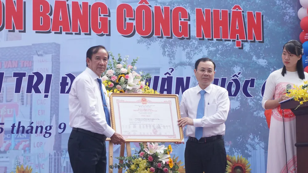 Ông Nguyễn Văn Hiếu, Phó Bí thư Thành uỷ TP.HCM (bìa phải) trao bằng công nhận trường đạt chuẩn quốc gia cho ông Mạch Công Thạch, Hiệu trưởng trường THCS Phan Văn Trị (bìa trái). Ảnh: NGUYỄN QUYÊN