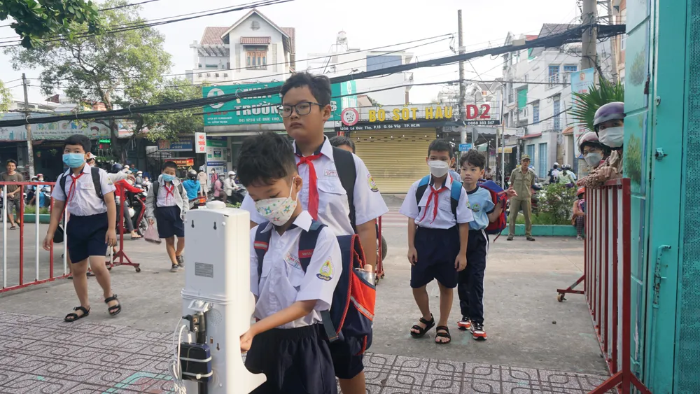 Nhà trường luôn quan tâm đến các biện pháp phòng dịch. Vì thế, trước khi vào trường, các em đều phải đo thân nhiệt và rửa tay sát khuẩn. Ảnh: NGUYỄN QUYÊN