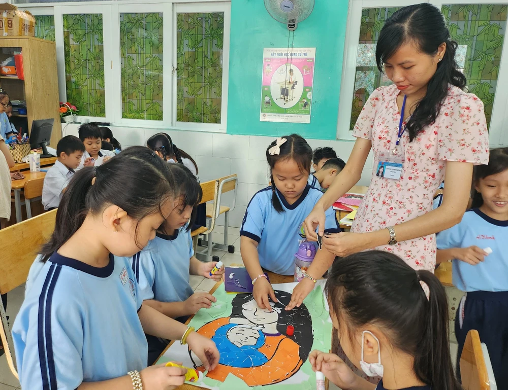 Cô trò cùng nhau xé giấy dán tranh.