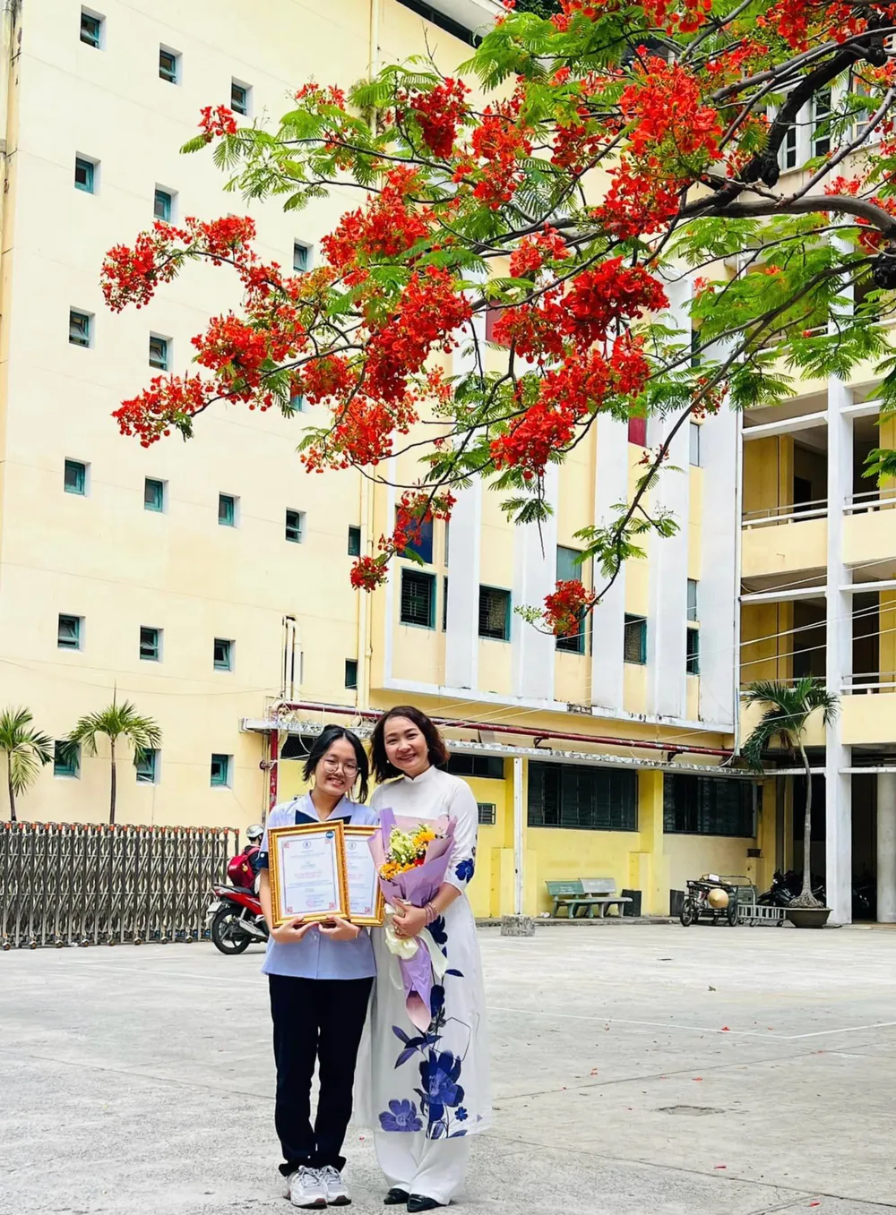 Cô Võ Kim Hiệp cùng học trò lưu giữ khoảnh khắc đẹp bên cây phượng &quot;rực lửa&quot;. Ảnh: KIM HIỆP