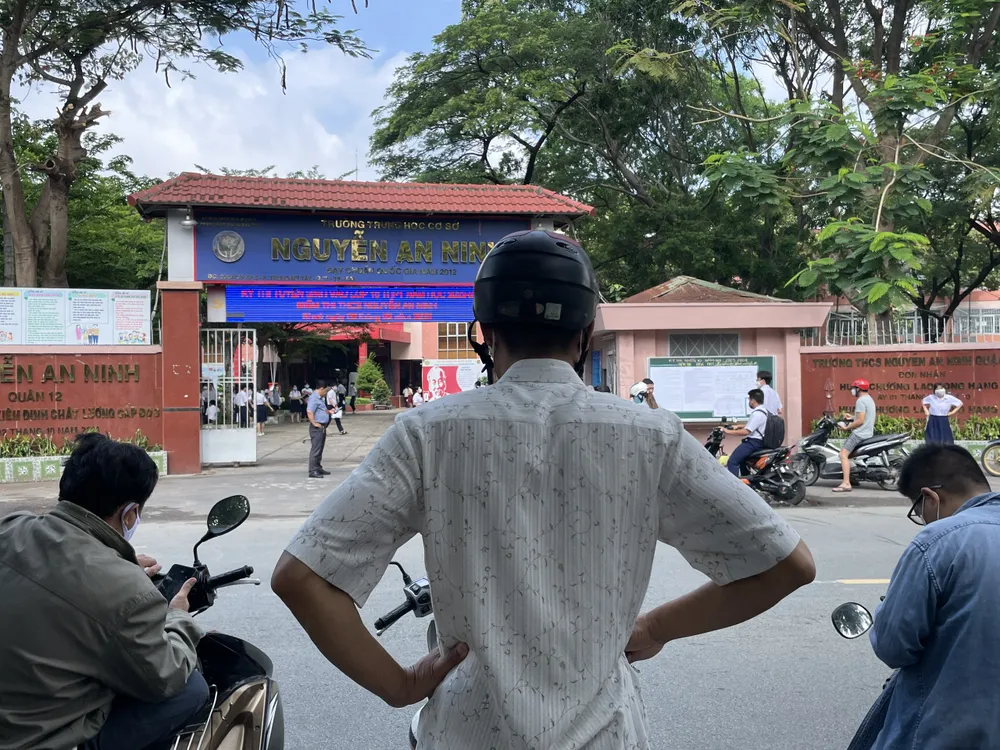 Phụ huynh đứng chờ trong khi con làm thủ tục dự thi. Ảnh: TRẦN MINH