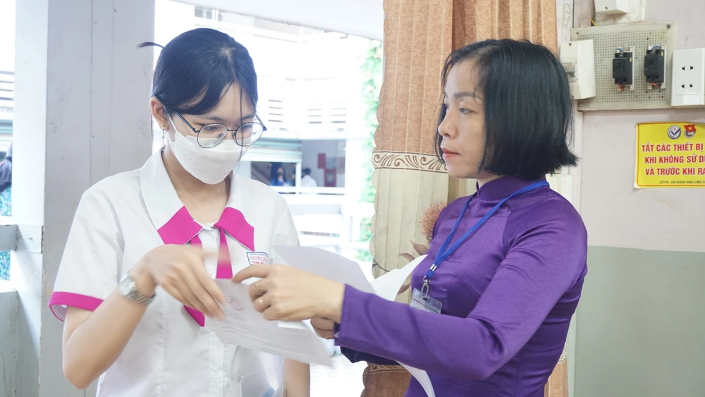 Giám thị kiểm tra giấy tờ của thí sinh trước giờ thi tại Hội đồng thi TP.HCM. Ảnh: NGUYỄN QUYÊN