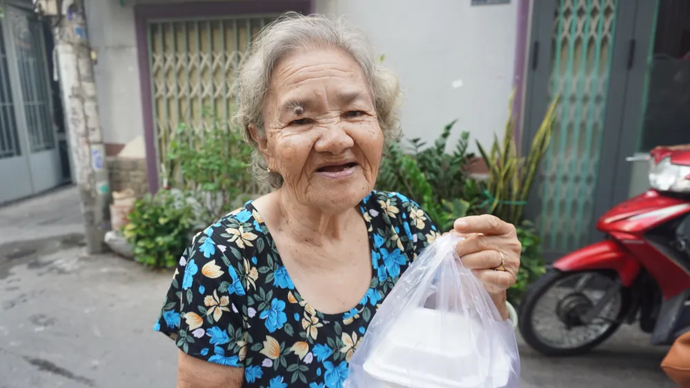 Bà Nguyễn Thị Nhen vui khi được nhận món xôi miễn phí. bua-sang-0-dong.JPG