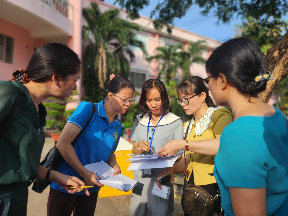Sau khi thí sinh đã vào phòng thi, các cô xem lại danh sách lần cuối để kiểm tra xem còn em nào chưa đến, tránh tình trạng các em ngủ quên hay đi trễ bỏ lỡ mất kỳ thi quan trọng của cuộc đời mình. Ảnh: NGUYỄN QUYÊN thi-vao-lop-10-1.jpg