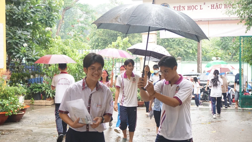 Thí sinh được các anh chị tình nguyện viên hỗ trợ đưa vào phòng thi, tránh bị ướt mưa. Ảnh: NGUYỄN QUYÊN thi-vao-lop-10-4.JPG