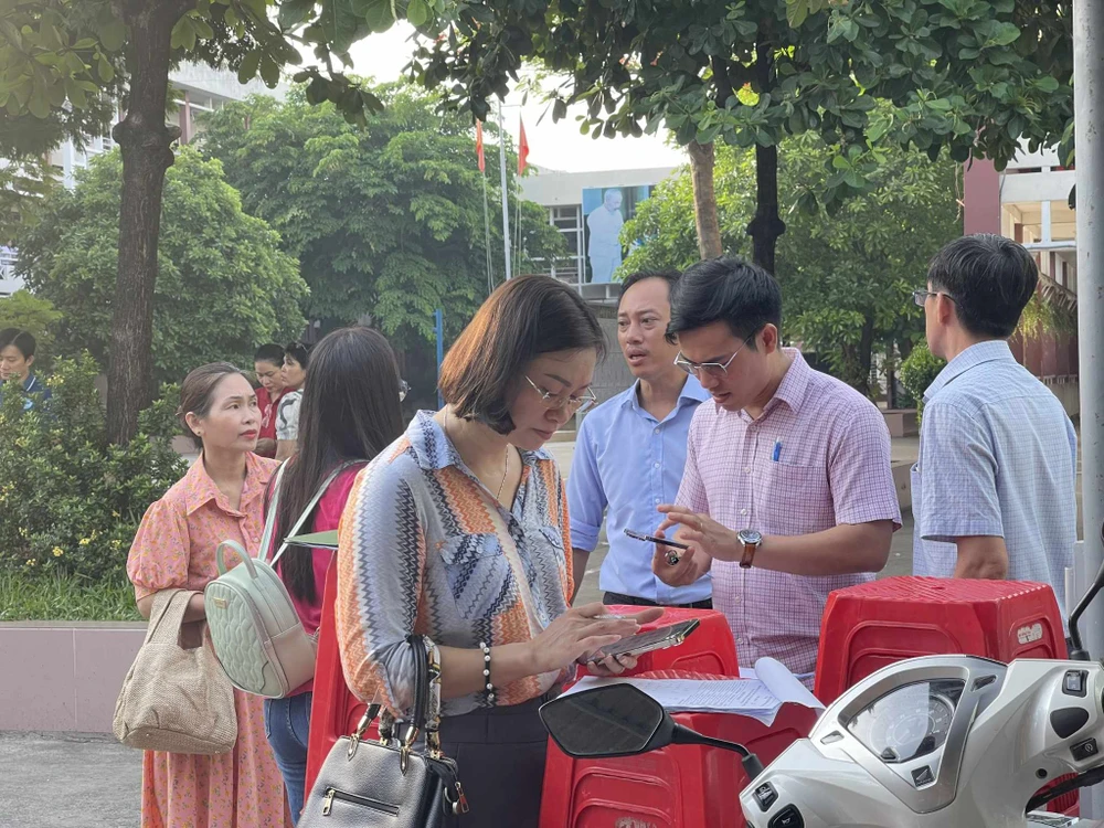 Giáo viên Trường THCS Nguyễn Trãi, quận Gò Vấp có mặt sáng sớm tại điểm thi để điểm danh và liên tục gọi điện nếu học trò chưa có mặt. Ảnh: TRẦN MINH thi vào lớp 10