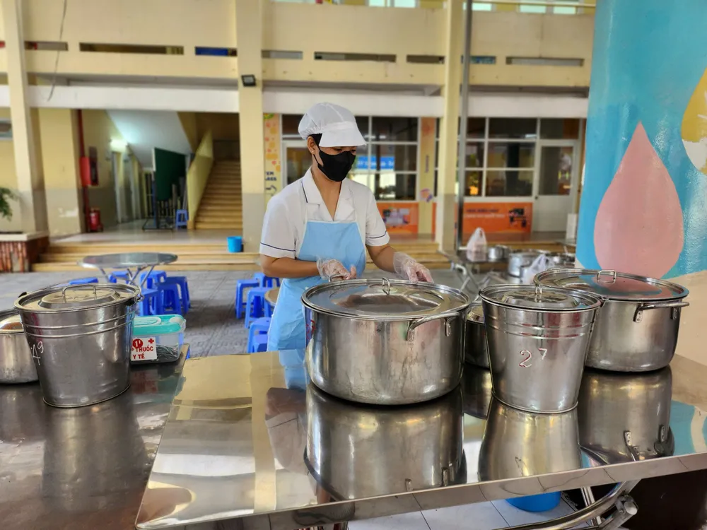 Nhân viên cấp dưỡng Trường Tiểu học Nguyễn Bình Khiêm, quận 1 chuẩn bị bữa ăn cho các con. Ảnh: NGUYỄN QUYÊN tien-an-ban-tru-3.jpg