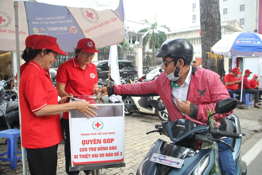 Người đi đường dừng lại quyên góp cứu trợ đồng bào bị thiệt hại do bão số 3. Ảnh: NGUYỄN QUYÊN hoi-chu-thap-do-tp.hcm.jpg