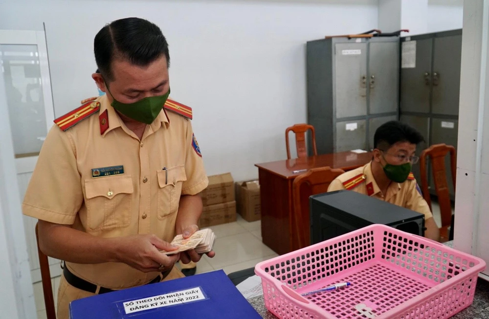 Các cán bộ đội đăng ký xe tại Công an huyện Nhà Bè đang thực hiện thủ tục đăng ký xe cho người dân.