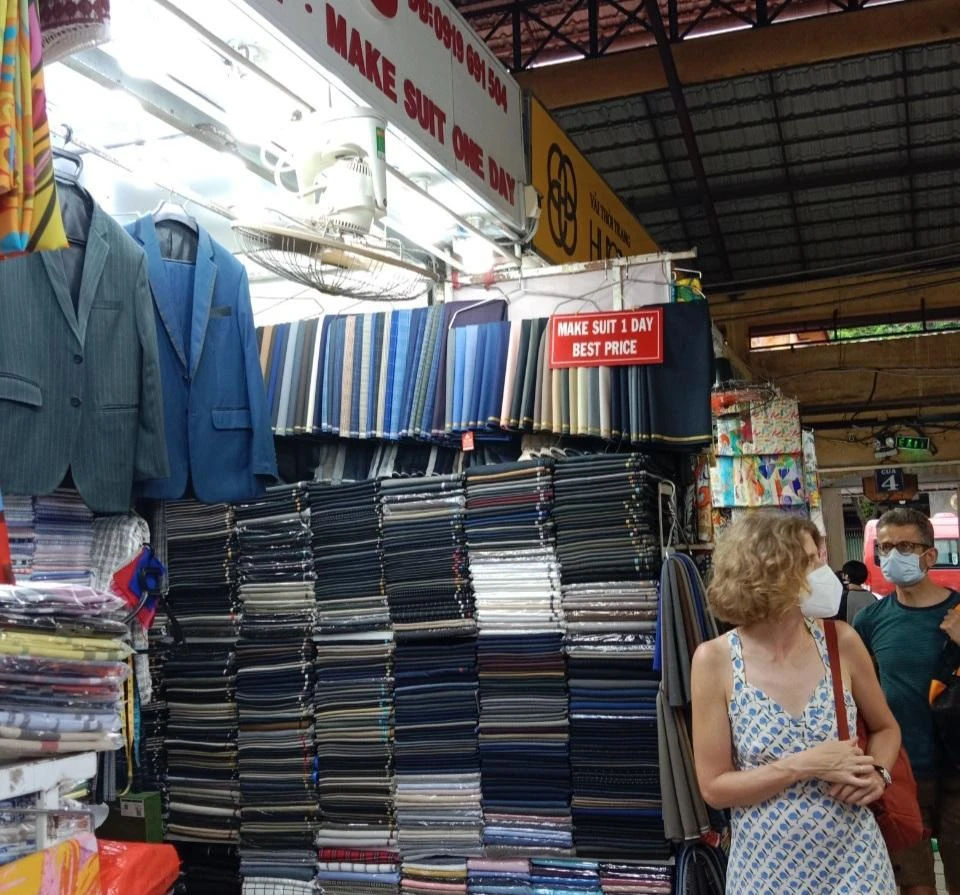 Các sạp vải chợ Bến Thành quảng bá dịch vụ may đo đồ vest trong ngày, với giá tốt.
