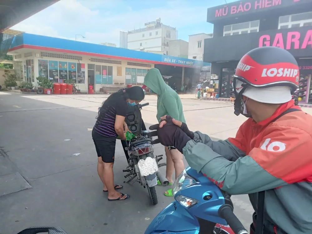 Một người phụ nữ hồ hởi khi mua được xăng trong chai nước ngọt để đổ vào xe máy mà không xếp hàng