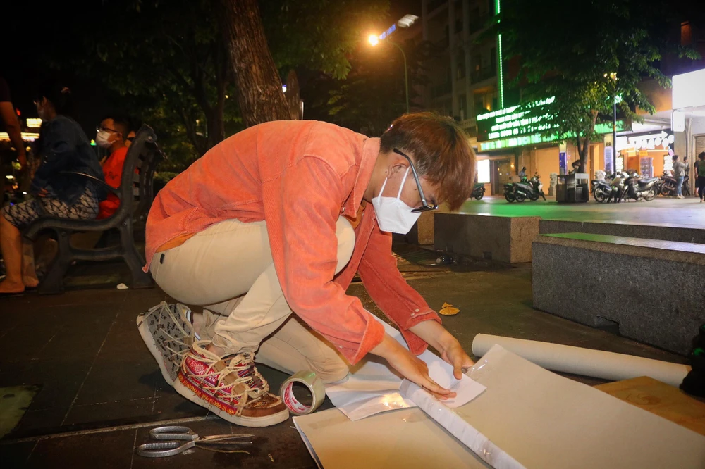 Chàng trai Phạm Thiên Ân cẩn thận chuẩn bị lại chiếc standee có một không hai của mình. Ảnh: TÚ NGÂN