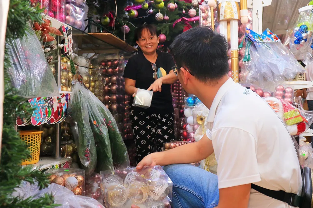Anh Đông Thiện được nhân viên bán hàng tư vấn nhiều loại phụ kiện trang trí. Ảnh: VÕ THƠ giới trẻ chi tiền triệu mua đồ trang trí giáng sinh