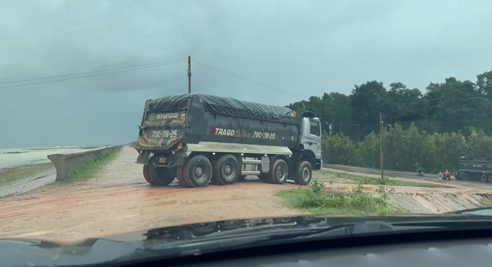 Xe chở cát vun cao quá thùng lưu thông qua thành đập Dầu Tiếng. Ảnh: VÕ TÙNG - TỰ SANG
