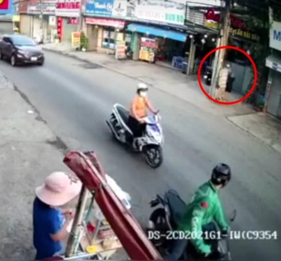 Người mặc áo xe ôm công nghệ đứng đợi đồng bọn đang lấy trộm xe máy bên đối diện đường vào sáng 28-3. Ảnh: Cắt từ clip