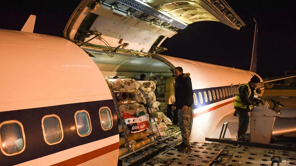 Công nhân bốc dỡ hàng viện trợ do Iran gửi tới tại sân bay ở TP Aleppo, phía bắc Syria vào sáng sớm ngày 8-2. Ảnh: AFP