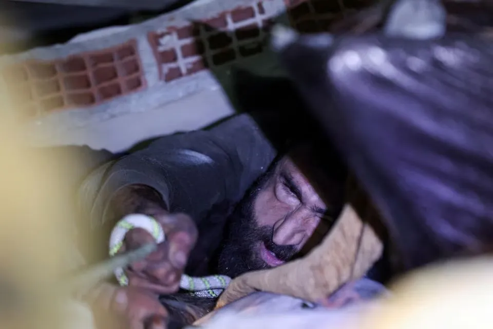 Ông Muaini bám vào một sợi dây để lực lượng cứu hộ đưa ông ra ngoài. Ảnh: REUTERS