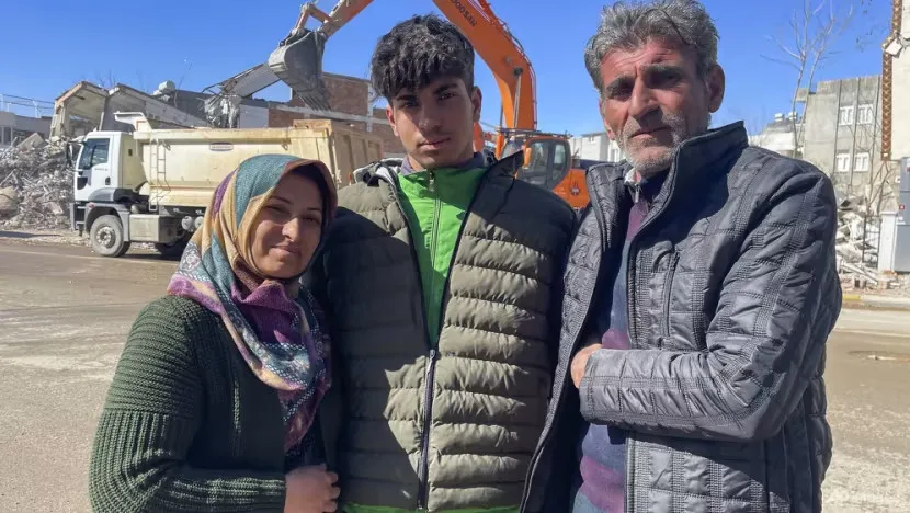 Cậu thiếu niên Taha Erdem (17 tuổi) cùng ba mẹ bên cạnh tòa nhà của gia đình bị phá hủy sau động đất ở TP Adiyaman, Thổ Nhĩ Kỳ, ngày 15-2. Ảnh: AP
